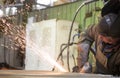 Factory worker grinding steel sheet with flying sparks