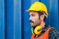 Factory worker man in hard hat and noise reduction ear muffs with containers box background
