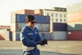 Factory worker man in sunglasses wearing gloves and holding hard hat at cargo container Royalty Free Stock Photo