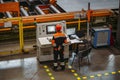Factory worker monitoring CNC machine in metalworking workshop