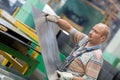 Factory worker moving metal sheet in workshop