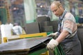 Factory worker removing metal burrs from steel sheet Royalty Free Stock Photo