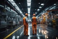 Factory workers converse, weaving connections as they walk through expansive production hall Royalty Free Stock Photo