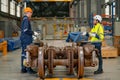 Factory workers man and woman discuss about work and stand in workplace with wheel and some parts of electric train are in front Royalty Free Stock Photo