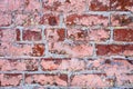 Faded cracked pink paint peeling from red brick wall in closeup Royalty Free Stock Photo