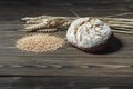 Fresh baked wheat bread loaf, a handful of wheat grain and wheat ears on a dark brown wooden background. Royalty Free Stock Photo