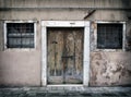 Faded old run down empty house in venice with cracked walls and bolted peeling wooden door with bars on the windows Royalty Free Stock Photo