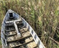 Faded wooden rowing boat in long grass marshes. Sun faded grey, Manteo, North Carolina, USA.