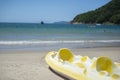 Faded yellow two-seater kayak moored on the sand of a beautiful beach in Brazil in a sea and blue sky landscape on background. Royalty Free Stock Photo