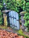 Aged gate with fading paint hangs from stone pillars in Portland, Oregon