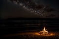 The fading glow of a beach bonfire under the starlit sky