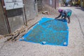 Fadiouth, Senegal, AFRICA - April 26, 2019: An unidentifiable Senegalese woman puts shells on a blue blanket and dries them in the Royalty Free Stock Photo