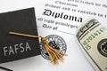 FAFSA Free Application for Federal Student Aid text on graduation cap with diploma and money Royalty Free Stock Photo