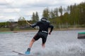 Young wakeboarder rides a wakeboard on the lake. Wakeboarding is cool, extreme sport Royalty Free Stock Photo