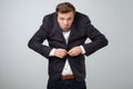 Fail in business concept. Young untidy man in big suit trying to fasten a button. He is feeling nervous Royalty Free Stock Photo