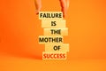 Failure or success symbol. Wooden blocks with words A failure is the mother of success. Beautiful orange table orange background.