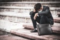 Failure unemployed stressed young Asian business man in suit covering head with hands. A young businessman sitting desperate on Royalty Free Stock Photo