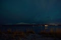 Faint aurora borealis on night sky over mountain and sea