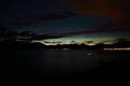 Faint aurora borealis over mountain and calm fjord