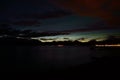 Faint aurora borealis over mountain and calm fjord