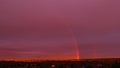 Rainbow arching across dramatic sunset sky over rooftops Royalty Free Stock Photo