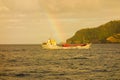 A faint rainbow over a cargo ship in the caribbean Royalty Free Stock Photo