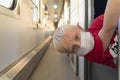 Fair-haired boy in protective mask on train compartment. Train travel rules during pandemic and quarantine Royalty Free Stock Photo