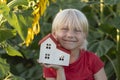 Fair-haired boy with small house is surrounded by field of sunflowers. Eco-friendly home. Green houses Royalty Free Stock Photo