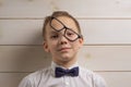 A fair-haired boy of 10 years in a white shirt with the self-tie bow tie with a serious expression on the background of a wooden Royalty Free Stock Photo