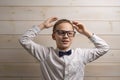 A fair-haired boy of 10 years in a white shirt with the self-tie bow tie with a serious expression on the background of a wooden Royalty Free Stock Photo