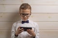 A fair-haired boy of 10 years in a white shirt with the self-tie bow tie with a serious expression on the background of a wooden Royalty Free Stock Photo