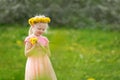 Fair-haired child girl in field of yellow dandelions. Little lady in pink dress holds flowers. Selective focus Royalty Free Stock Photo