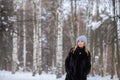 fair-haired girl in a blue hat, black fur coat against the backdrop of a snowy winter birch forest Royalty Free Stock Photo