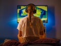 A fair-haired girl gamer sits in front of a large TV screen and plays a video game. Close-up. Shot from the back. Gaming, fun Royalty Free Stock Photo