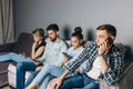 Fair-haired guy is talki g on the phone while his fiends are surfing the Net