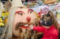 Fair. Halloween. Girl examines and touches pumpkin dressed up as a man's head.