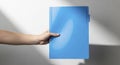 Fair skinned hand holding a vibrant blue plastic folder against a white background with shadows Royalty Free Stock Photo