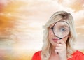 Fairhaired woman looking through a magnifying glass