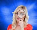 Fairhaired woman looking through a magnifying glass