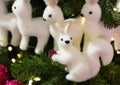 Fairy christmas tree toy white squirrel small sitting on a spruce branch holding a bumpkin on the background