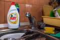 Fairy dishwasher liquid on focus, dirty cutlery and plates on the background.