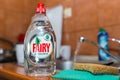 Fairy dishwashing liquid on kitchen sink, flowing tap water in the background.