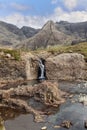 Skye\'s Fairy Pools invite with calm waters and mountainous backdrop, showcasing wild beauty