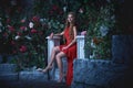 Fairy tale. Beautiful princess in red dress sitting in a mystical garden