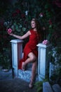 Fairy tale. Beautiful princess in red dress sitting in a mystical garden