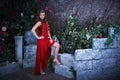 Fairy tale. Beautiful princess in red dress sitting in a mystical garden