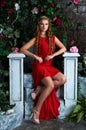 Fairy tale. Beautiful princess in red dress sitting in a mystical garden Royalty Free Stock Photo