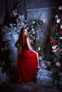 Fairy tale. Beautiful princess in red dress sitting in a mystical garden Royalty Free Stock Photo