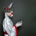 Fairy tale character. Woman hare holding pigeon bird on black background. Halloween makeup costume Royalty Free Stock Photo