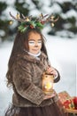 Fairy tale girl. Portrait a little girl in a deer dress with a painted face in the winter forest. Big brown antler